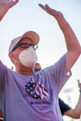anonymous man in respiratory mask standing with raised arms
